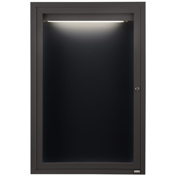 An Aarco bronze anodized aluminum cabinet with a black door and light on it.