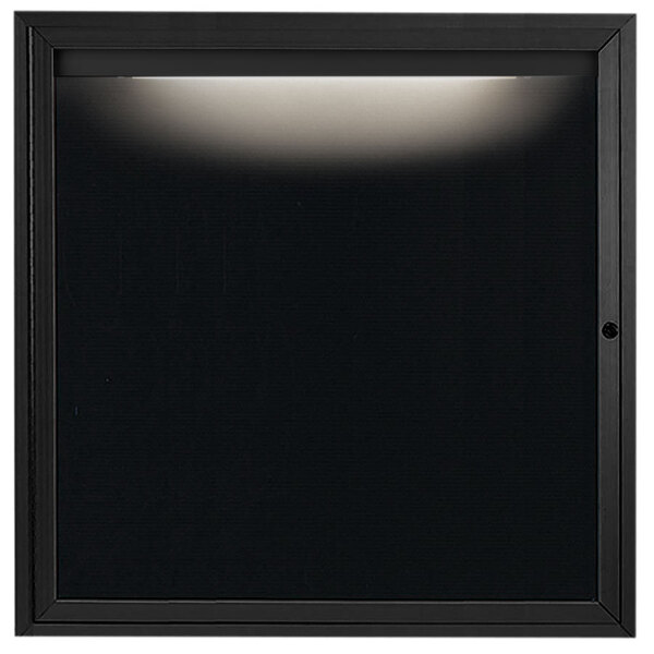 A black square Aarco outdoor message center with a light on it.