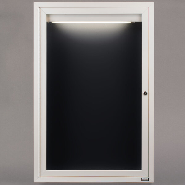 A white rectangular door with a black board inside and a light on it.