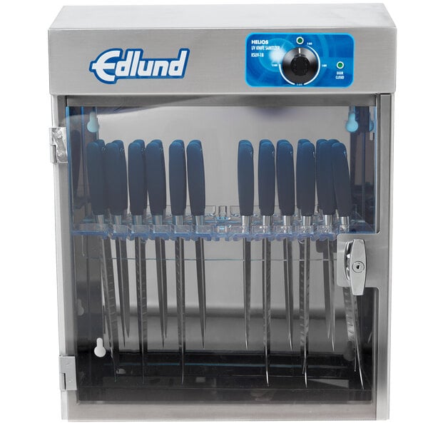 A metal Edlund knife sterilizer cabinet on a counter with knives inside.