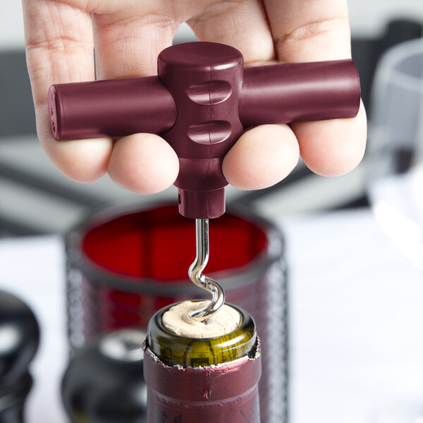 A hand holding a Franmara Burgundy plastic pocket corkscrew and opening a bottle of wine.