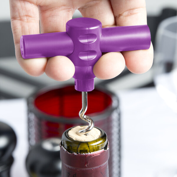 A hand using a Franmara purple plastic pocket corkscrew to open a wine bottle.