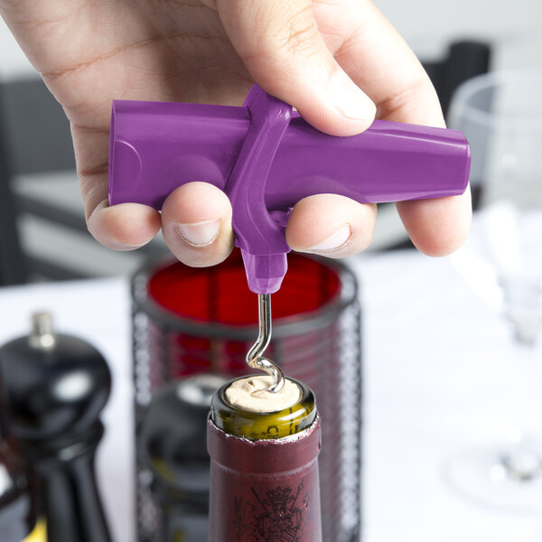 A person using a Franmara Traveler's Grape plastic corkscrew with purple accents to open a wine bottle.