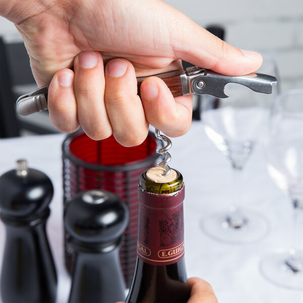 A person using a Laguiole Waiter's Corkscrew to open a bottle of wine.