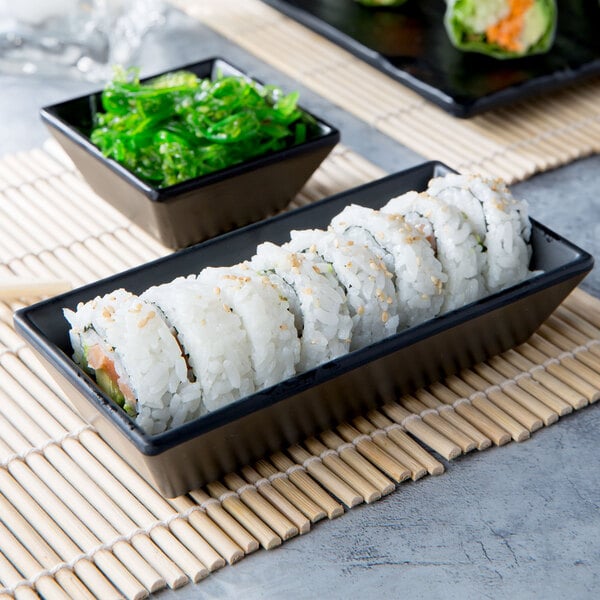 A sushi roll in a black Elite Global Solutions rectangle ramekin.
