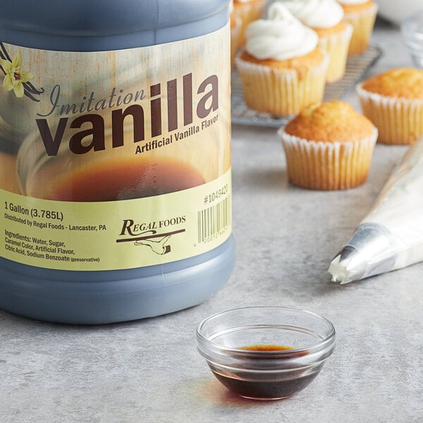 A bottle of Regal Imitation Vanilla next to cupcakes with a frosted cupcake on top.