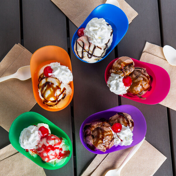 A table with four assorted color mini baseball helmet bowls filled with ice cream.