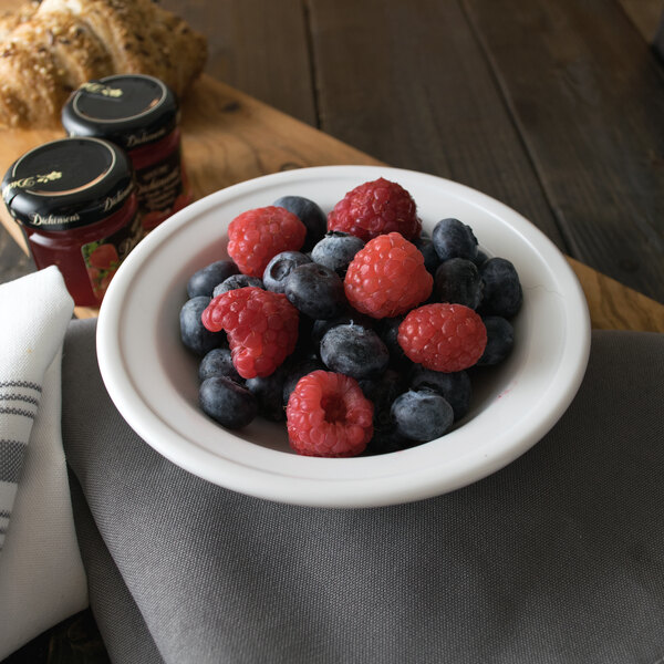 A Libbey alpine white porcelain fruit bowl filled with blueberries and raspberries on a table.