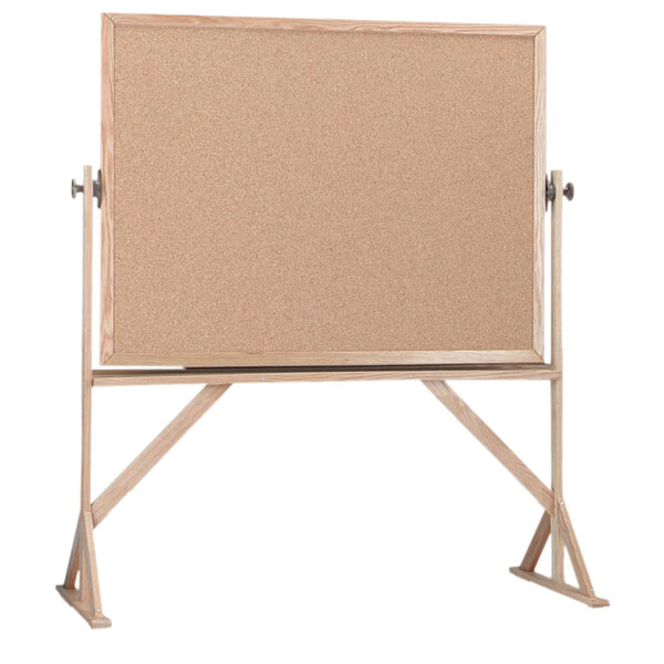 A Aarco cork board with a wooden frame on a stand.