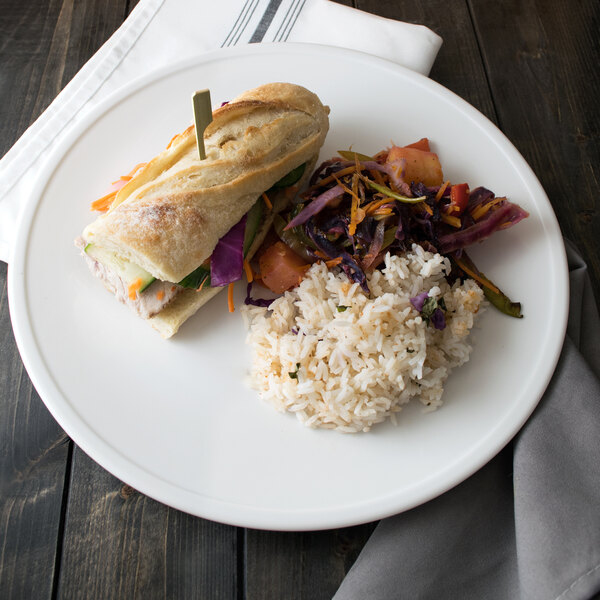 A Libbey Alpine White Porcelain Coupe Plate with a sandwich, rice, and vegetables.