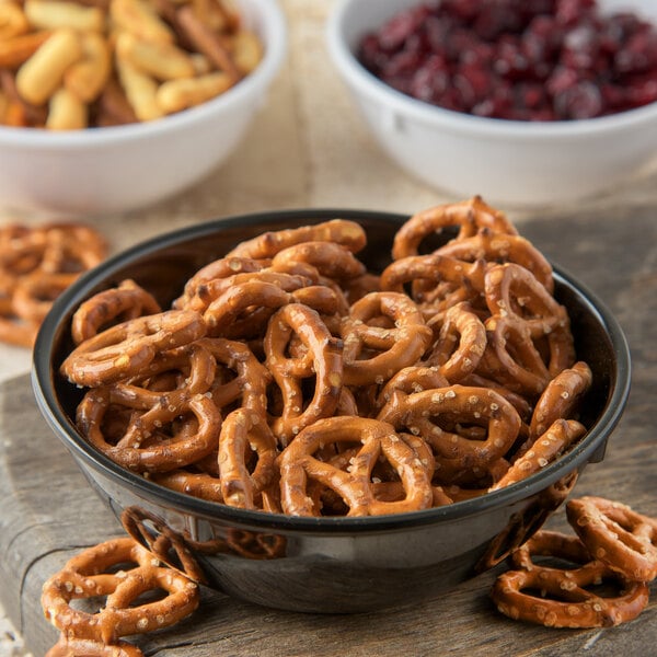 A Carlisle Dallas Ware black melamine nappie bowl filled with pretzels and other snacks.