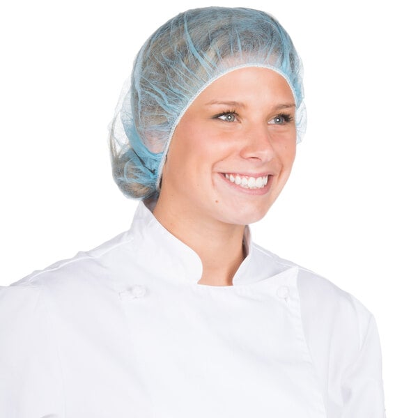 A woman in a white coat and blue hair net.
