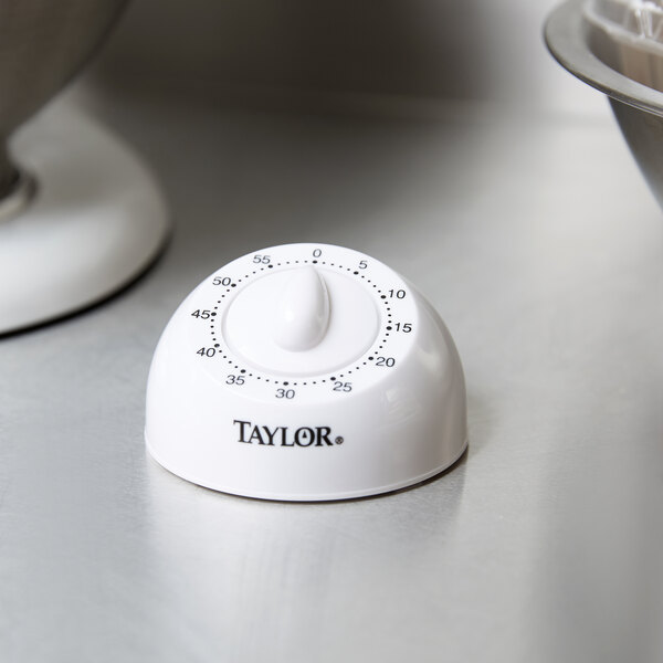 A white Taylor 5832 kitchen timer on a counter next to a bowl of dough.