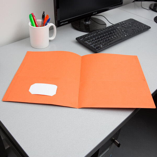 An orange Oxford 2-pocket folder on a desk.