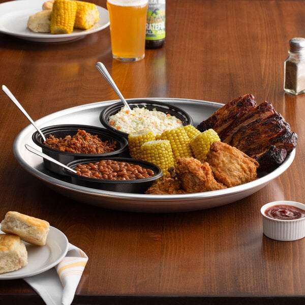 An aluminum Choice tray with ribs, corn, and other food on it.