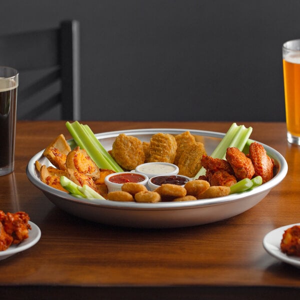 A Choice aluminum tray with chicken wings, vegetables, and a glass of beer on a table.