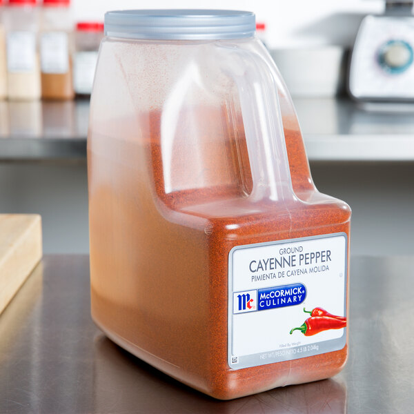 A container of McCormick Culinary Ground Cayenne Pepper on a counter with other spices.