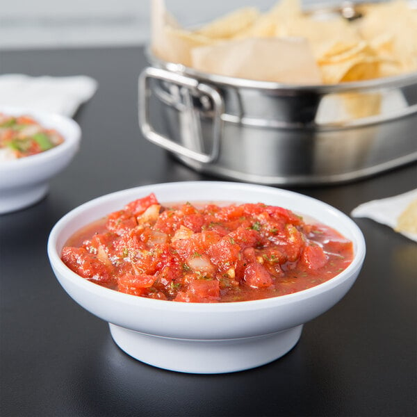 A white melamine Thunder Group salsa bowl on a table full of salsa.
