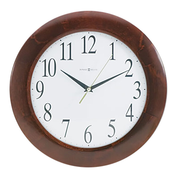 A close up of a Howard Miller cherry wood wall clock with black numbers and a minute hand.