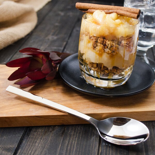 A dessert in a glass with a Walco stainless steel dessert spoon and cinnamon sticks.