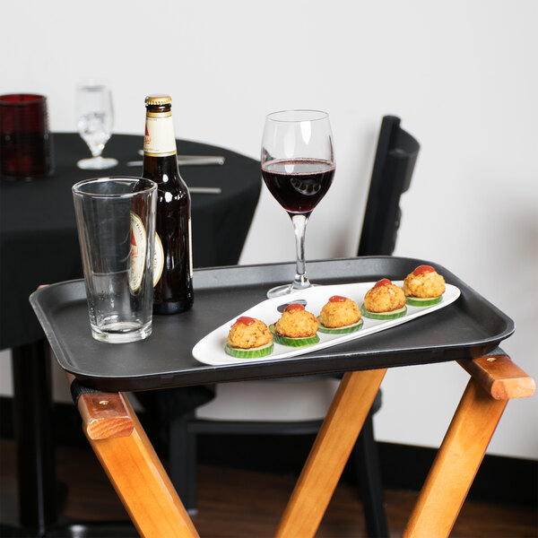 A black Cambro non-skid serving tray with food and a glass of wine on it.