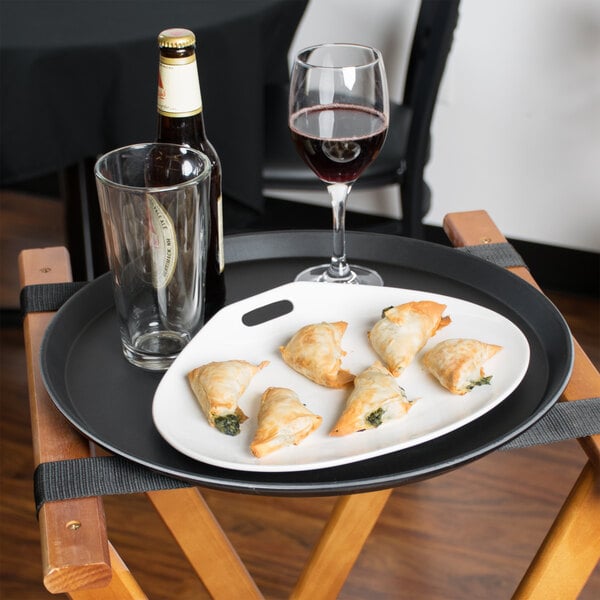 A Cambro non-skid serving tray with food and a glass of wine on it.