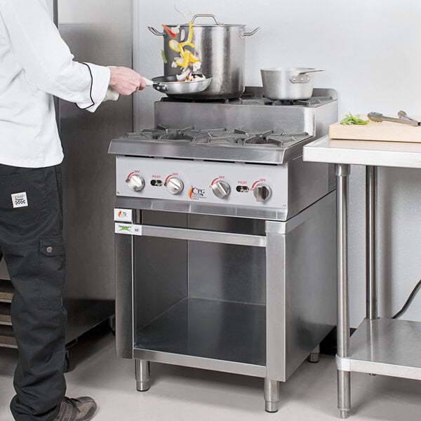 A person cooking food on a stainless steel Cooking Performance Group stove.