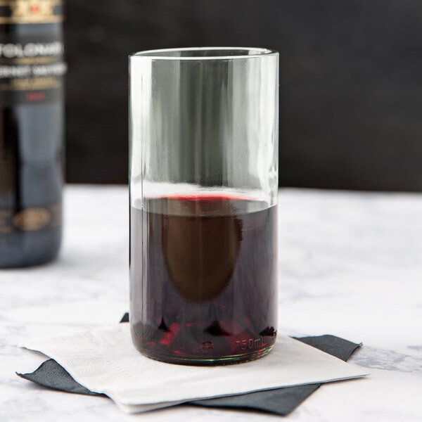 A Libbey Spanish Green wine tumbler filled with red wine on a table.