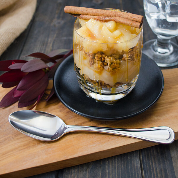 A glass of apple cinnamon dessert with a Walco Lisbon stainless steel dessert spoon and a cinnamon stick.