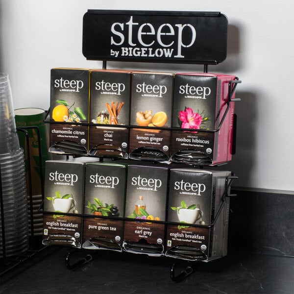 A Steep by Bigelow tea rack holding tea bags with a black and white label that says "Steep" on a counter.