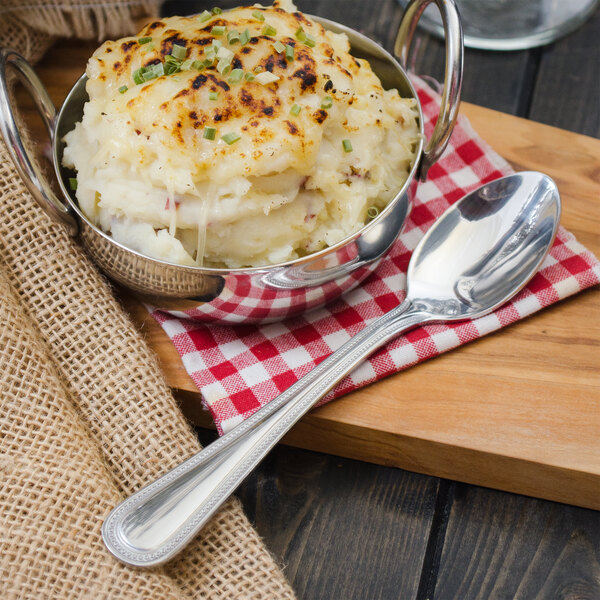 A bowl of mashed potatoes with a Walco stainless steel teaspoon in it.