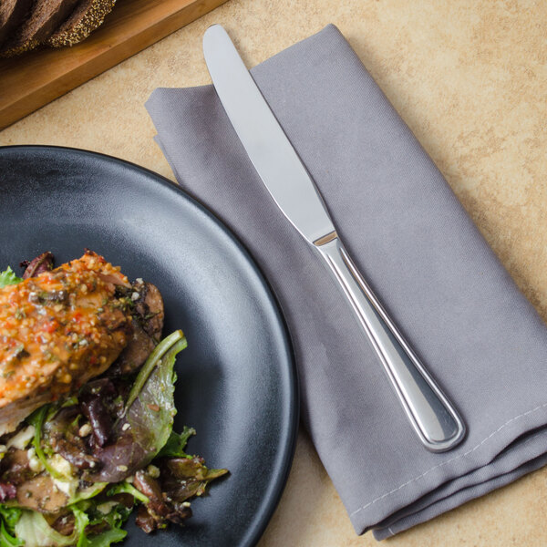A plate of food with a Walco Balance European table knife on a napkin.