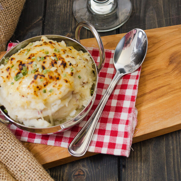 A bowl of mashed potatoes with a Walco Lisbon teaspoon on a wood cutting board.