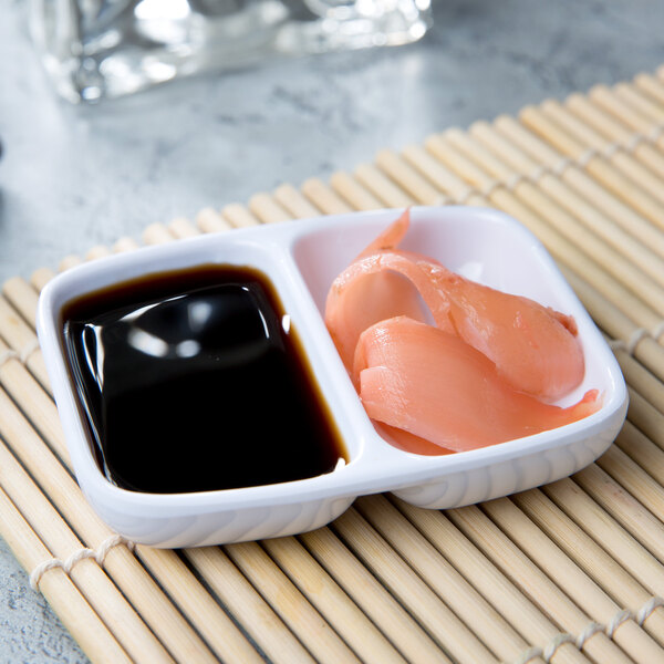 A white Thunder Group twin sauce dish with sushi and black sauce.
