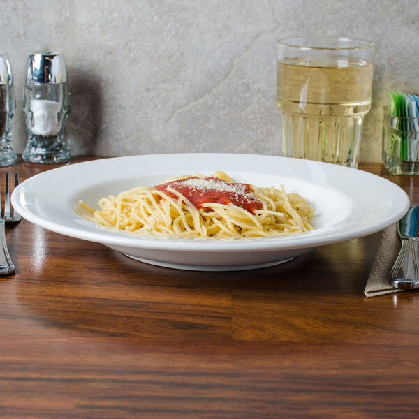 A plate of spaghetti with sauce and parmesan cheese in a Homer Laughlin bright white china bowl.