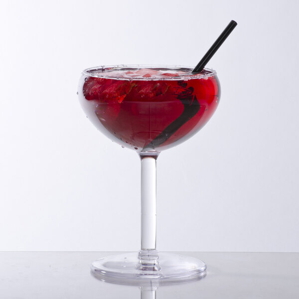 A GET SAN plastic coupe glass filled with red liquid and a black straw on a table
