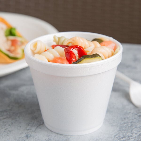 A Dart white foam food container filled with pasta and vegetables.