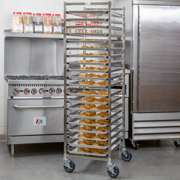 A tall, stainless steel rack on wheels holds multiple trays of baked goods in a commercial kitchen setting.