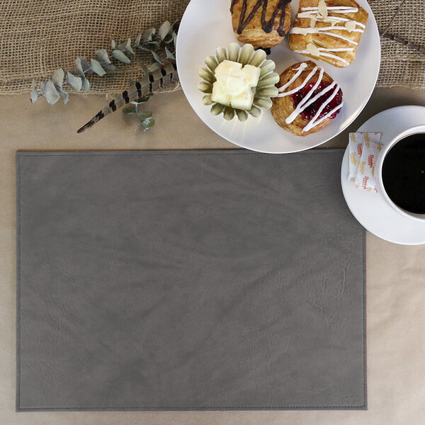 A white rectangular placemat with a cup of coffee and pastries on a white plate.