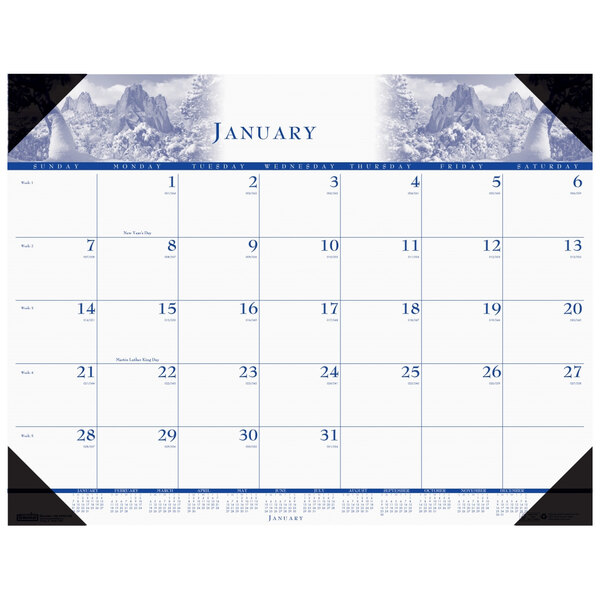 A House of Doolittle desk pad calendar with a blue and white design featuring a photo of snow-covered mountains.
