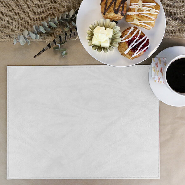 A white H. Risch, Inc. rectangle placemat with a plate of pastries and a cup of coffee.