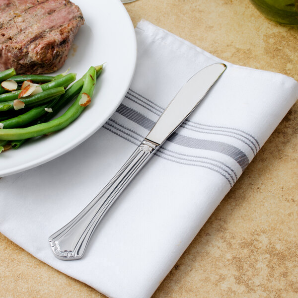A white plate with green beans and a Walco stainless steel dinner knife.