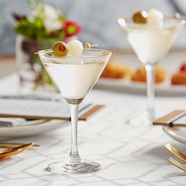 Two martini glasses with drinks on a table.