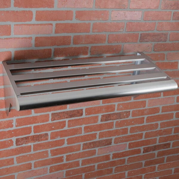 A stainless steel Matfer Bourgeat wall mounted shelf and rack on a brick wall.