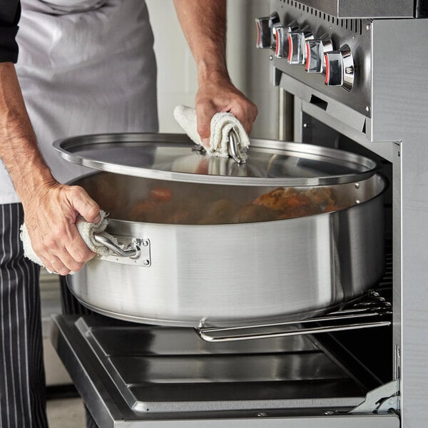 A person using a Vigor Stainless Steel Brazier to prepare food in a professional kitchen.
