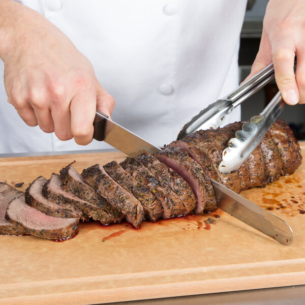 A chef using a Victorinox rosewood carving knife to slice meat.