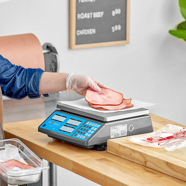 A person weighing meat on a AvaWeigh digital price computing scale on a deli counter.