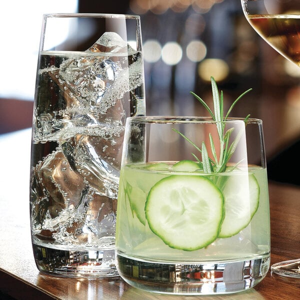 A close-up of a Chef & Sommelier highball glass filled with water and a cucumber slice.