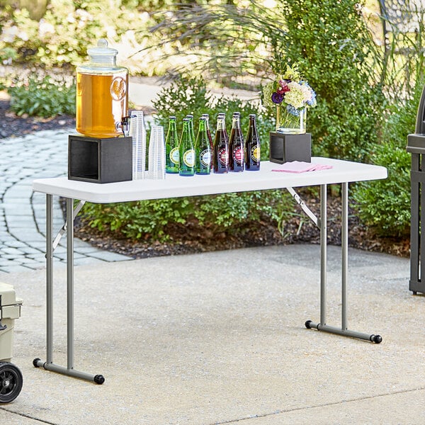 A Lancaster Table & Seating granite white folding table with drinks and bottles on it.