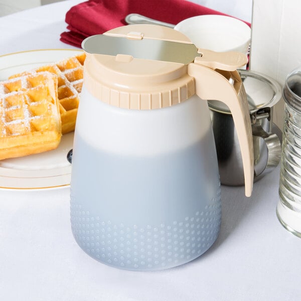 A Tablecraft almond dispenser with a pitcher of liquid next to waffles on a table.